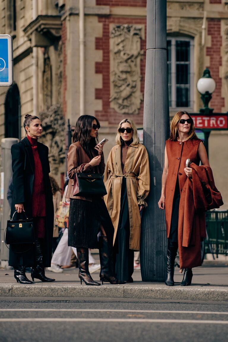 four women standing on the street at paris fashion week in trendy fall clothing
