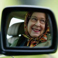 Queen Elizabeth II''s smiling reflection in the mirror of her Land Rover