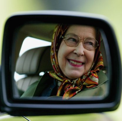 Queen Elizabeth II''s smiling reflection in the mirror of her Land Rover