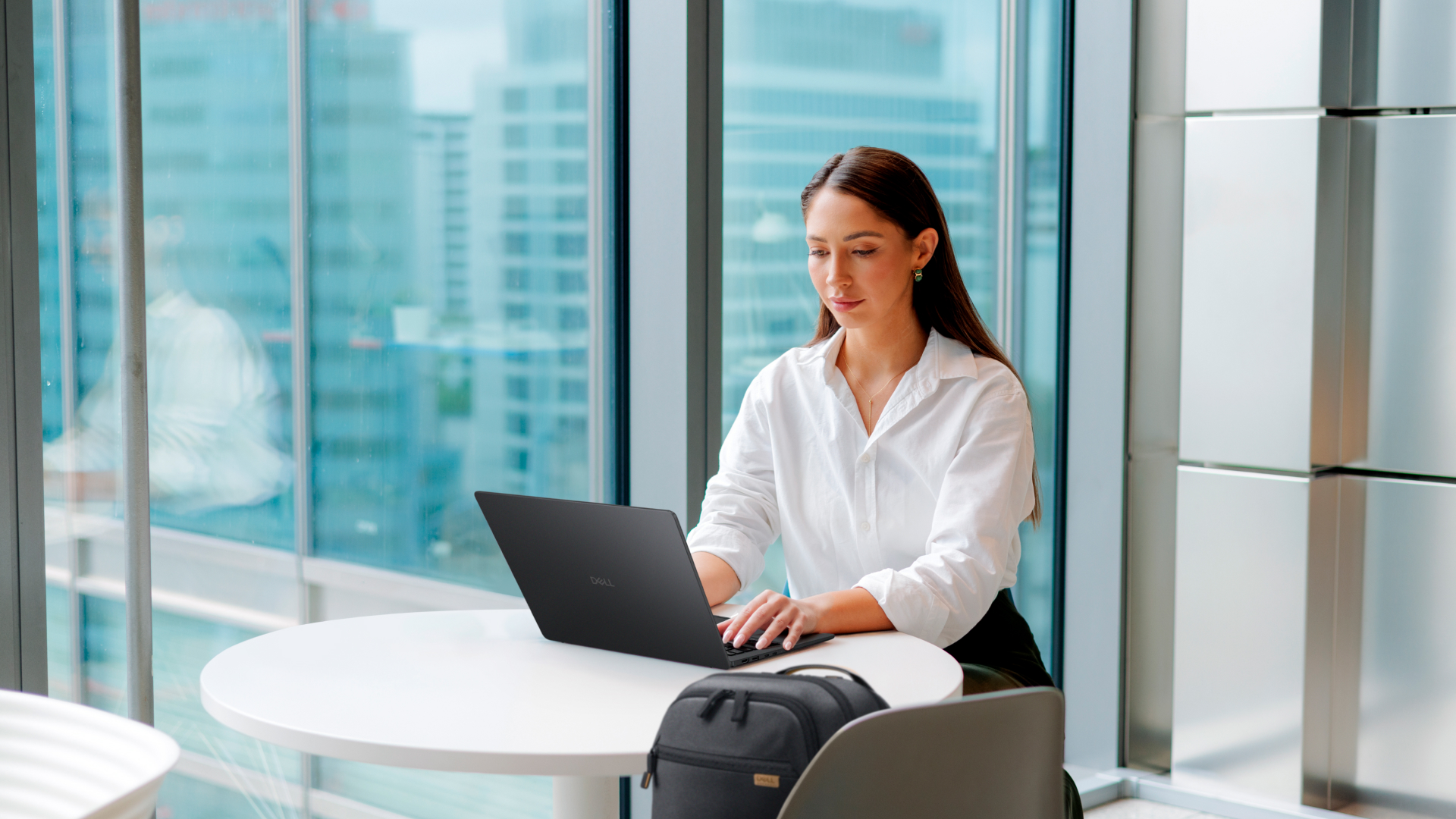 Dell Pro laptop being used by a person sat at a small circular desk in an office