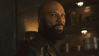 Common looks ahead in an office with a satisfied smile on his face in Silo S2 E3 - "Solo."