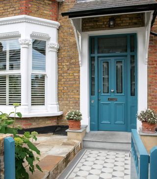 house with exposed brick walls and flowers pots on both sides of blue door