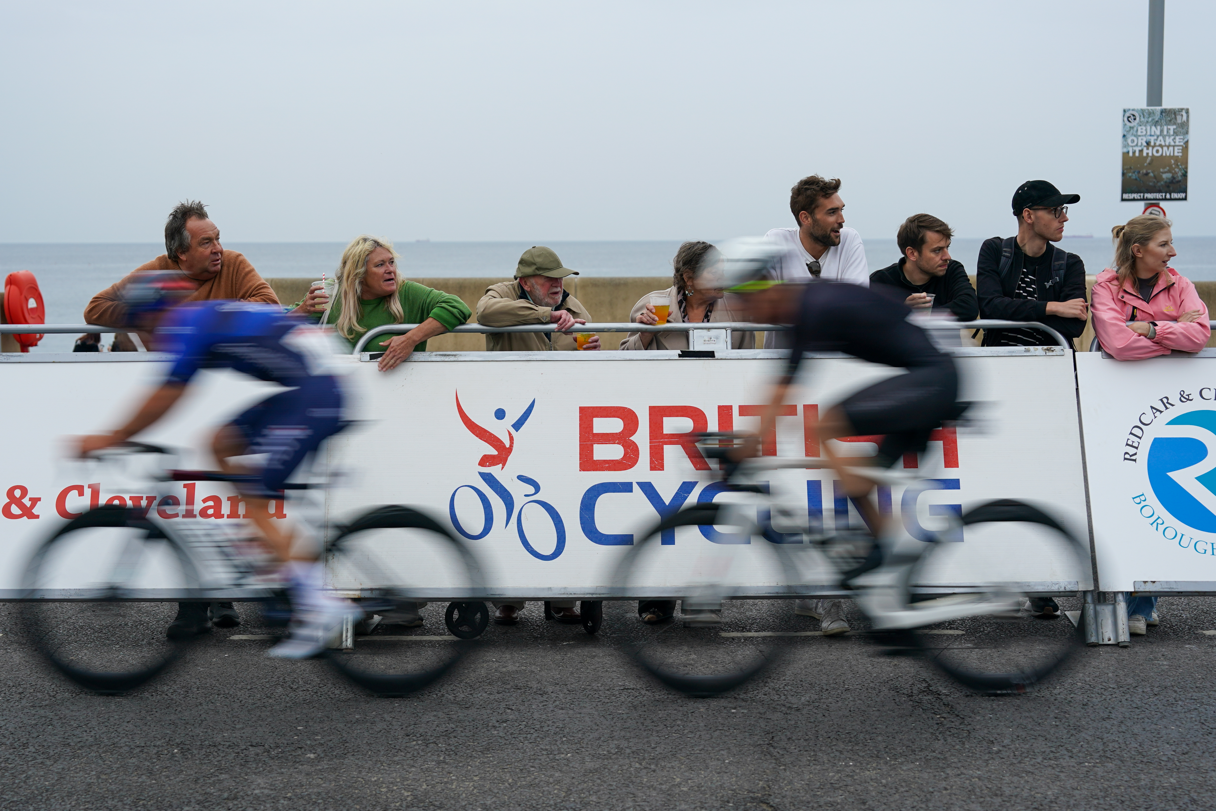 Blurry cyclists race past Britsh Cycling banner