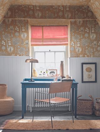 An office space with a blue desk, a wallpapered ceiling, and two wicker baskets