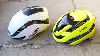 Lumos Ultra Fly Pro bike helmet in neon yellow next to the Abus Gamechanger 2.0 helmet in white