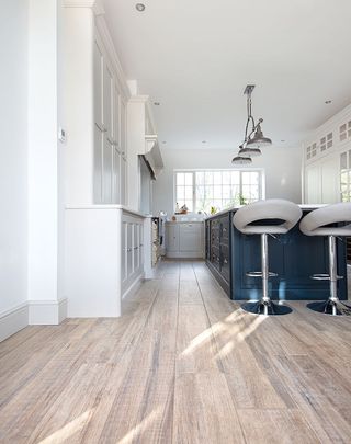 dark blue and white kitchen cabinets with planks of porcelain tile wood effect floor