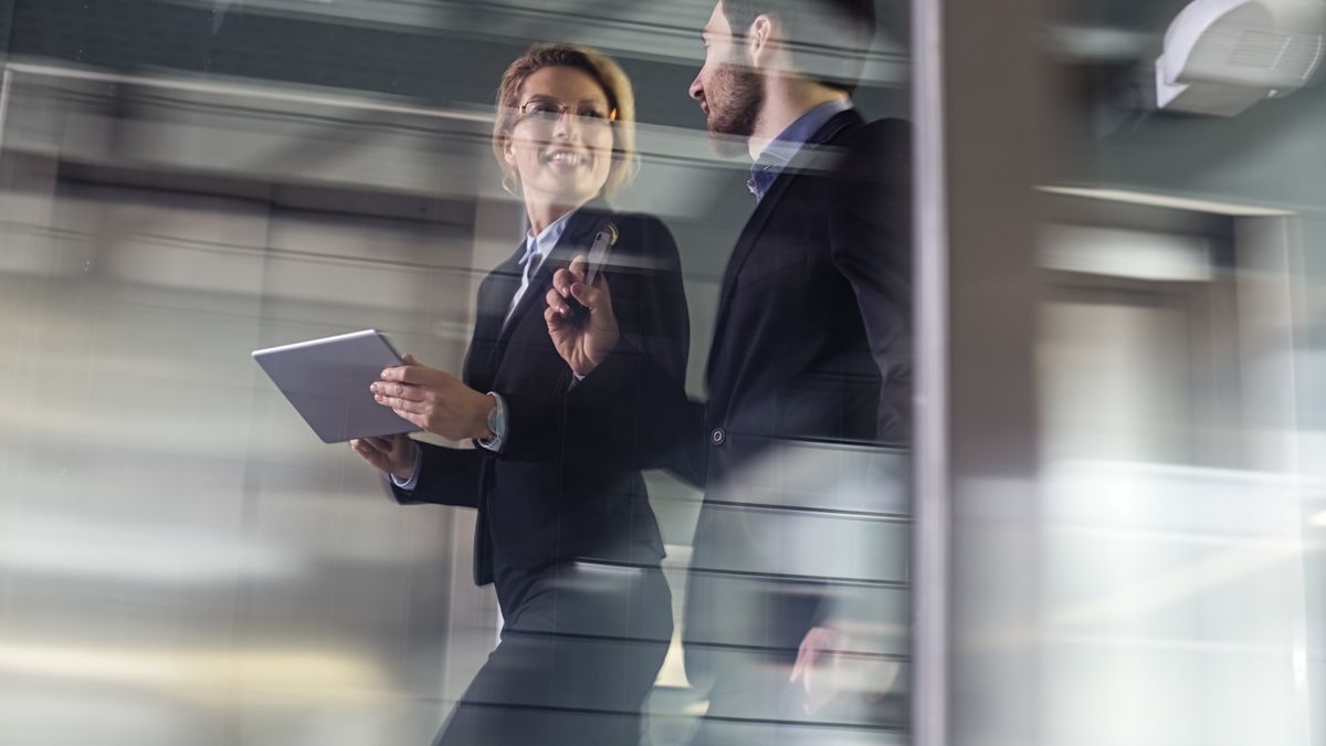 Two blurry business people moving quickly throughout a hectic day.