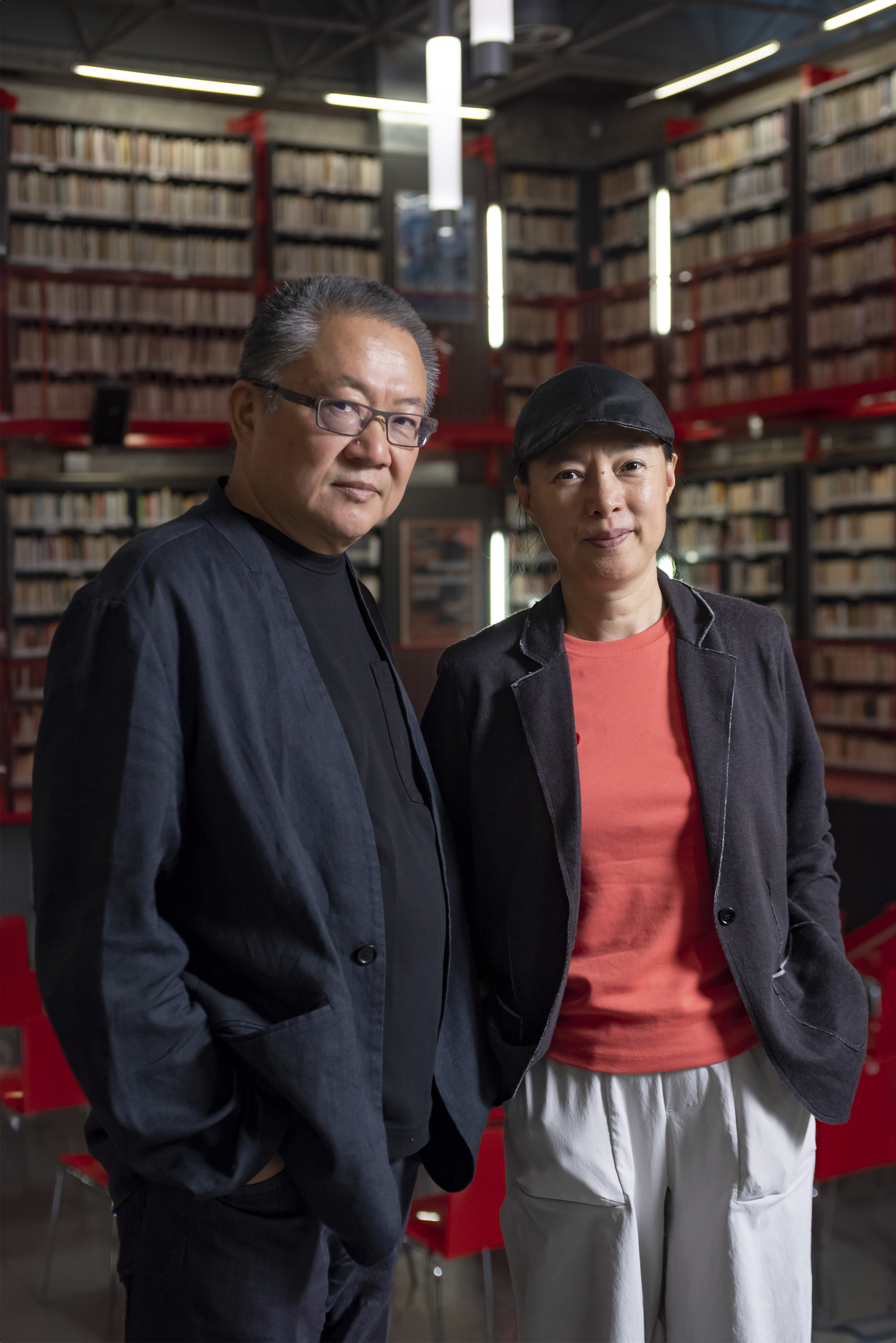 portrait of architects Weng Shu and Lu Wenyu, in front of bookshelves, at the announcement of them being curators for the 2027 venice architecture biennale