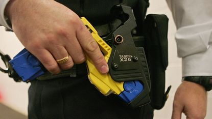 Police officer holsters a taser gun 