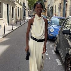 Woman wears white dress with black belt around the waist. 