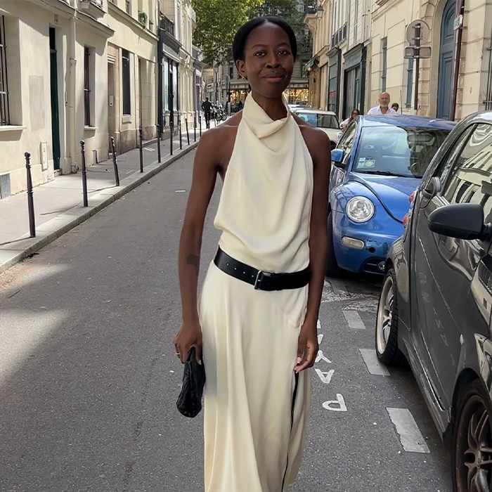 Woman wears white dress with black belt around the waist.