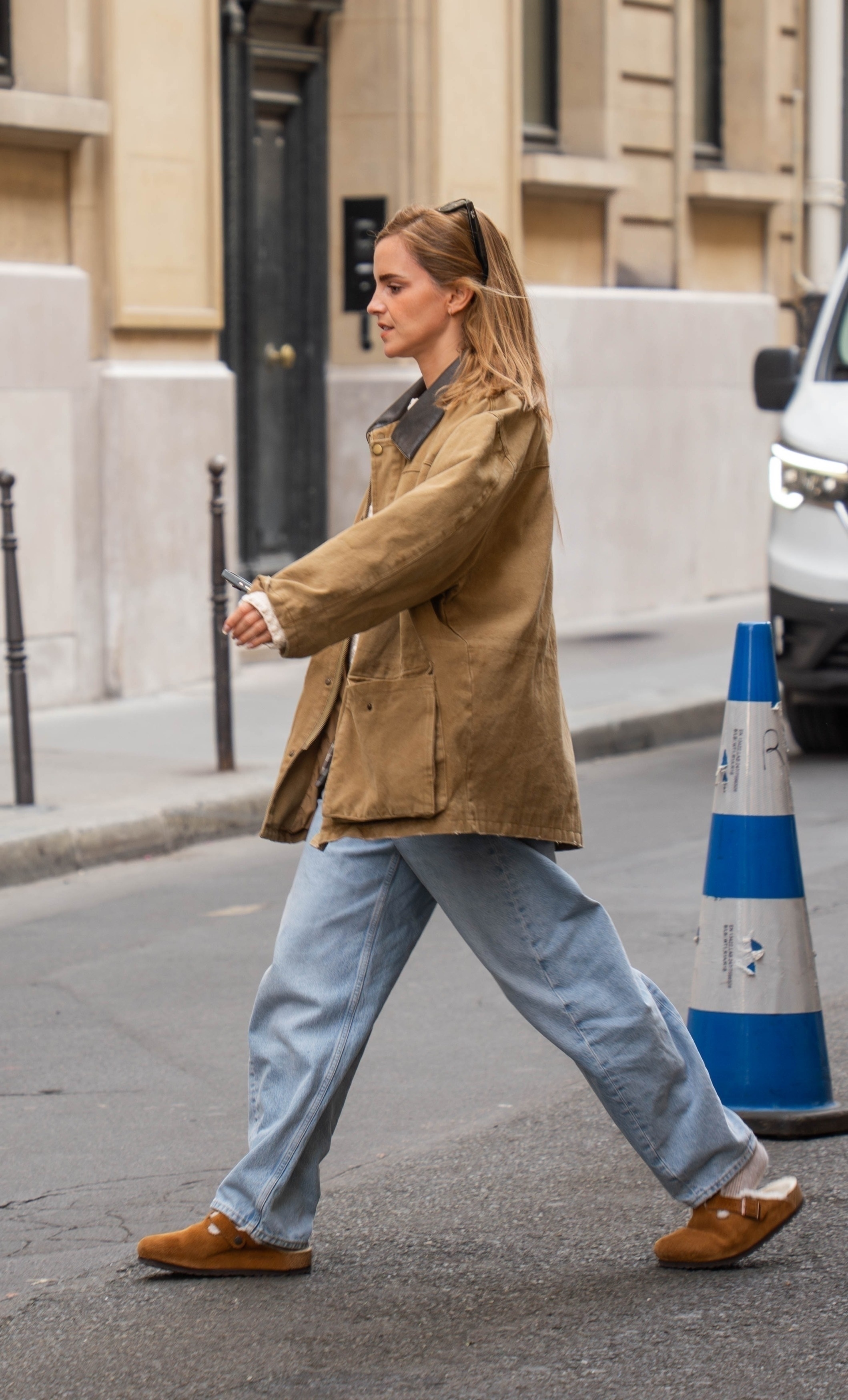 Emma Watson steps out in Paris wearing a barn jacket in a light brown shade with straight-leg jeans and Birkenstock clogs.