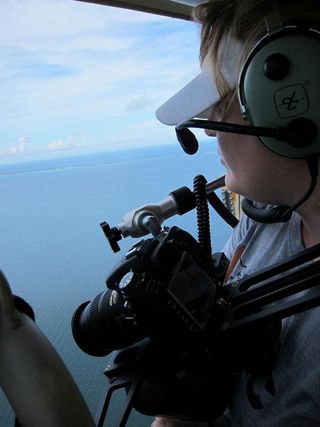 Marine biologist Kasey Cantwell taking aerial photographs out the open door of the helicopter at 1,000 feet.
