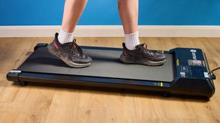 the deerrun q1 mini under desk treadmill walking treadmill in a home office with a blue wall and wooden floor
