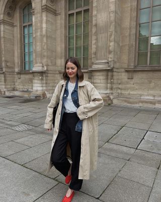 Woman wearing red shoes with black trousers, denim jacket, and trench coat.