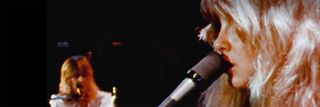 Christine McVie playing keyboards while Stevie Nicks sings.