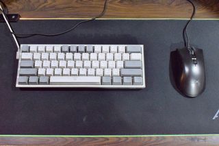 A 60% keyboard on a desk next to a black mouse.