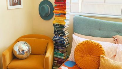 Bedroom with orange accent chair, stack of books, and disco ball
