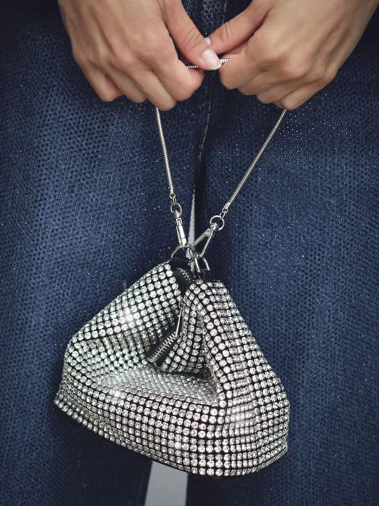 A model holding a crystal embellished Reiss pouch bag.