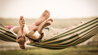 Two people resting in a hammock, only their feet showing.