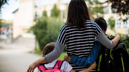 Rear view of mother taking two kids to school