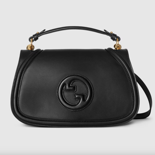 a black gucci blondie bag in front of a plain backdrop