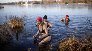 Group of women exploring the benefits of cold water swimming together in a lake wearing swimwear