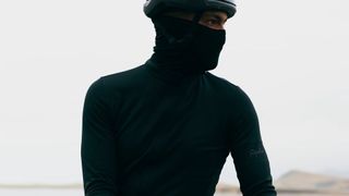 A man wears the Rapha Pro Team Thermal base layer pulled up above his face