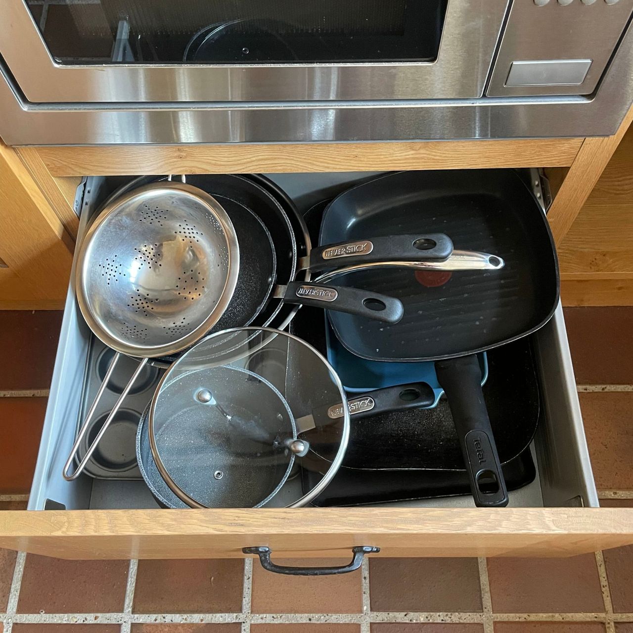 Jumble of messy pots and pans in a kitchen drawer
