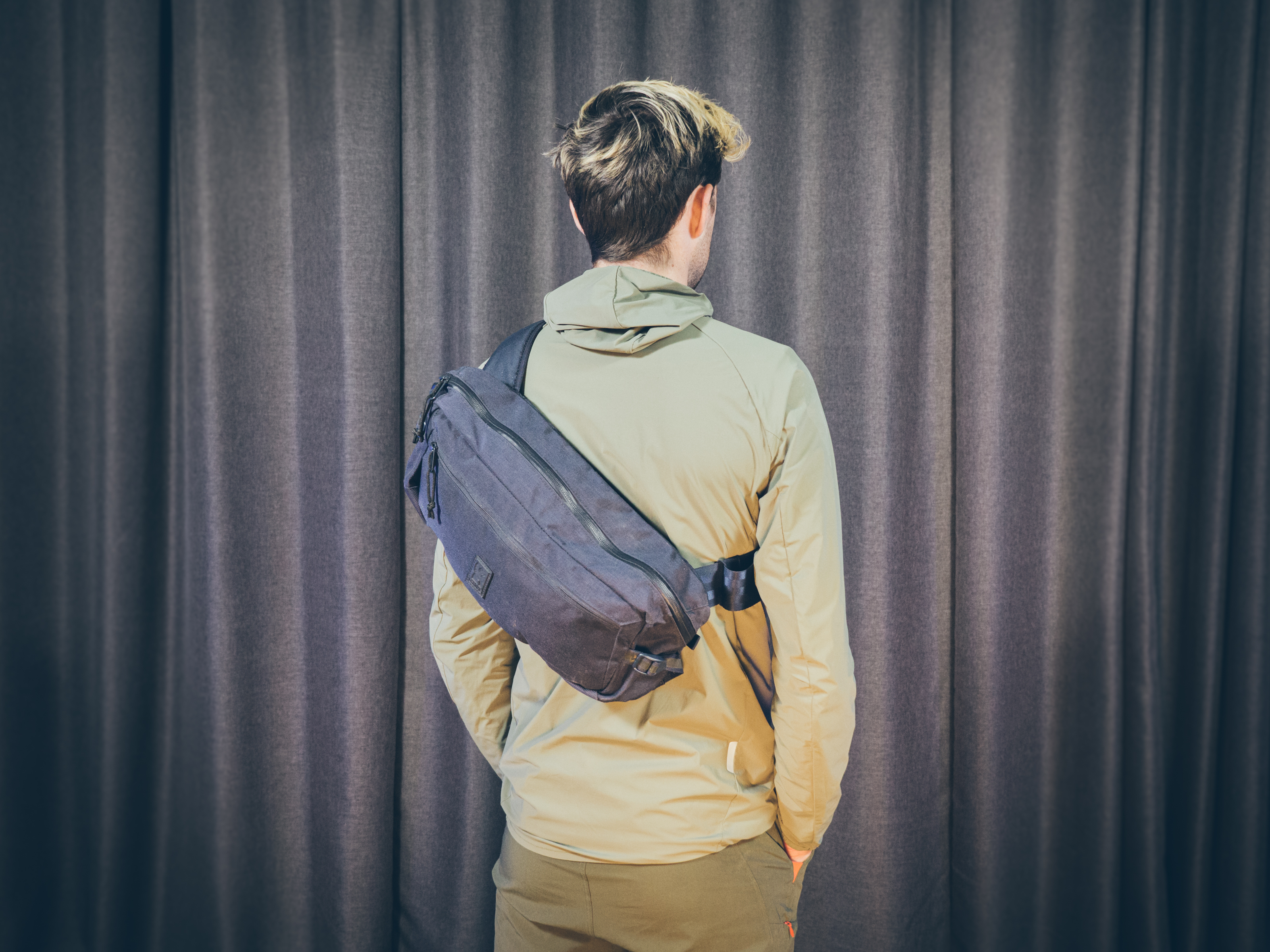 Will Jones, wearing one of the best backpacks for cycling, stands in front of a wall