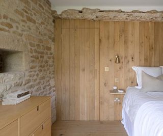 bedroom with new timber clad walls housing sockets and switches while stone walls are restored and include orginal features such as niches