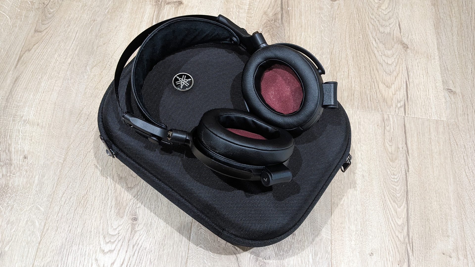 Yamaha YH-C3000 over-ear headphones on top of case on light wooden flooring