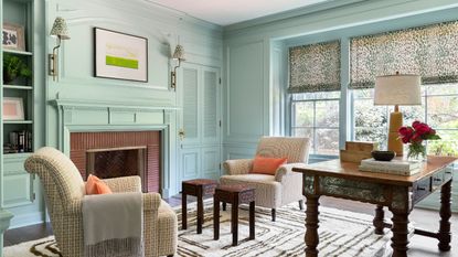 libarary with aqua walls fireplace and two patterned armchairs 