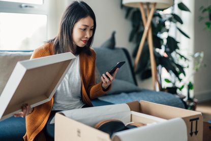 Beautiful Young Woman With Smartphone Receiving Parcel Purchased Online