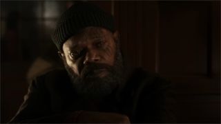 A still from Secret Invasion, a TV show from Marvel Studios. Here we see a close up of Nick Fury. He has 3 scar lines over his left eye, a big black beard and is wearing a black beanie and dark jacket.