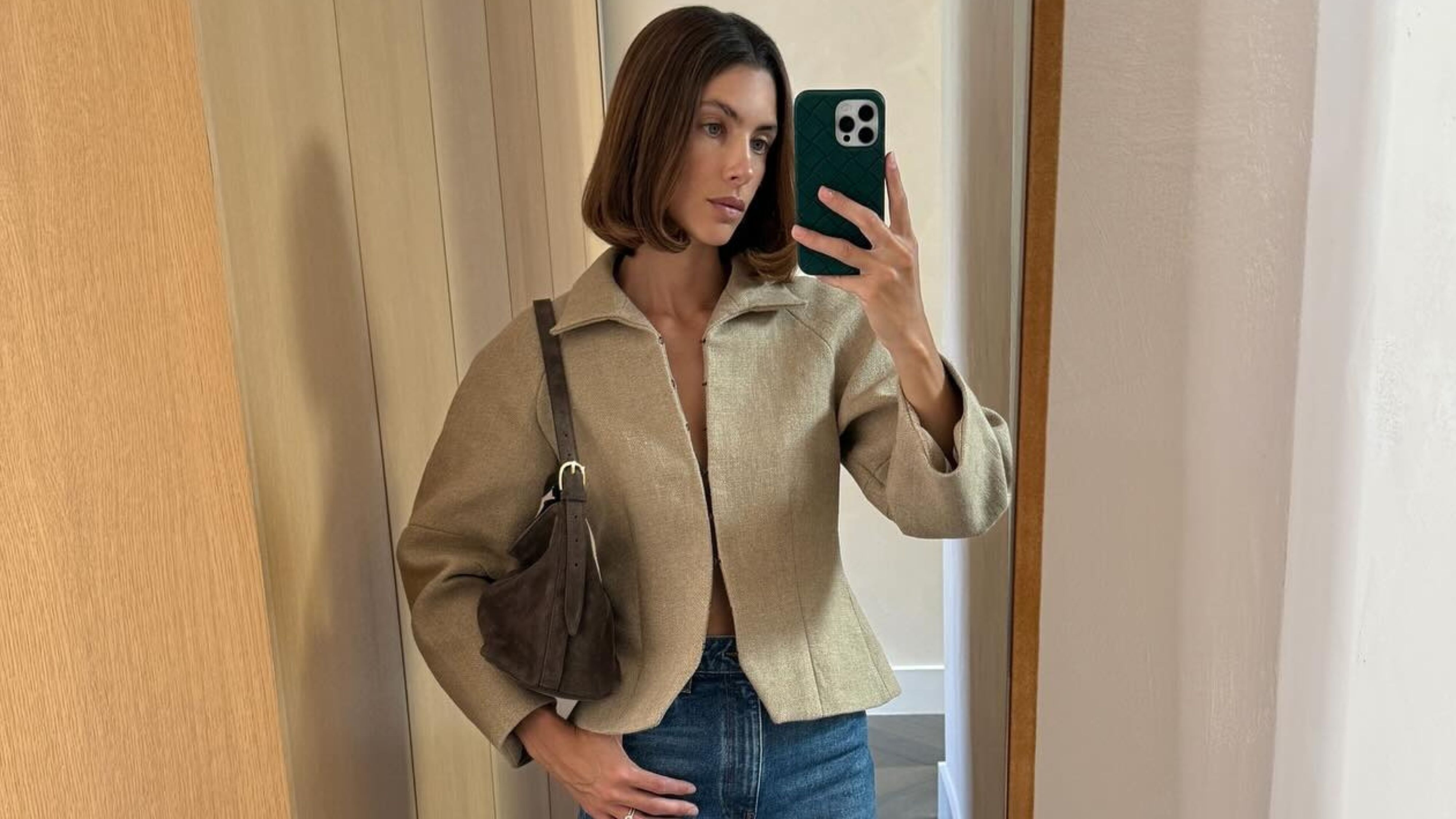 @jaimeridge wearing a cinch-waist jacket and jeans.