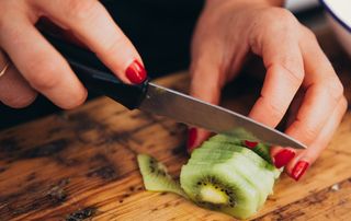 Woman slicing kiwi fruit