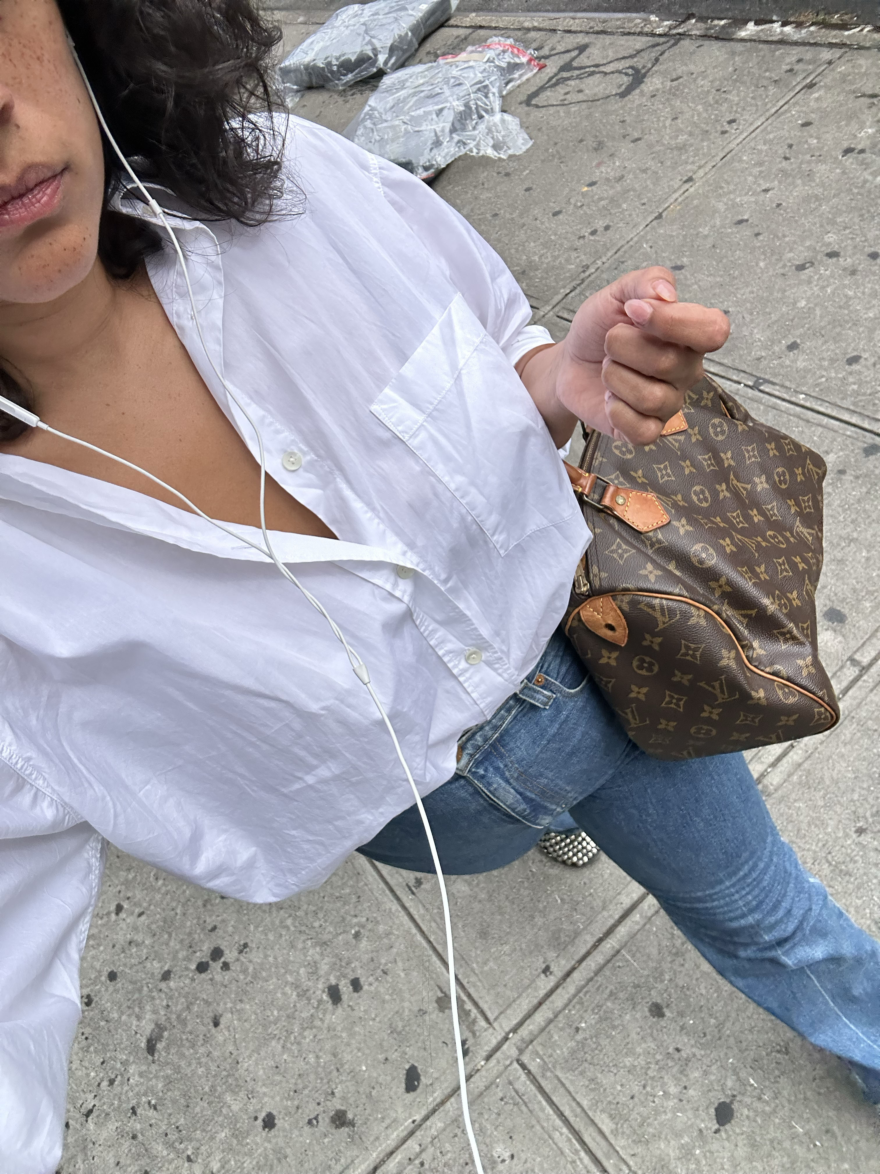 Jennifer Atile&amp;#769;mile walking down the street wearing a white button-down and jeans.