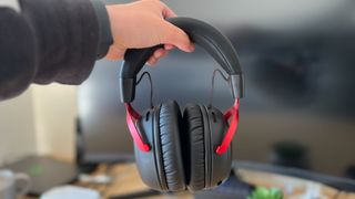 Reviewer holding HyperX Cloud 3 Wireless in front of gaming setup