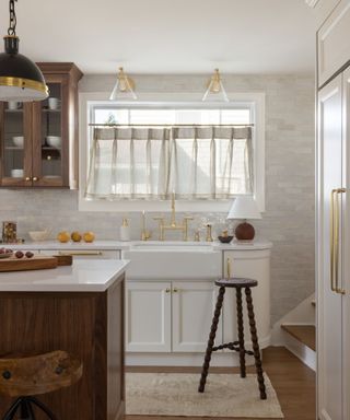 Neutral kitchen with cafe curtains a wood island, gold hardware and ambient lighting. Interior by Danielle Rose Designs