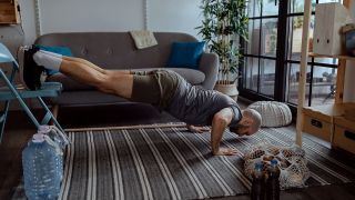 Man performs decline press-up using a sofa