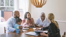 A multigenerational family talks with a financial adviser at their dining room table.