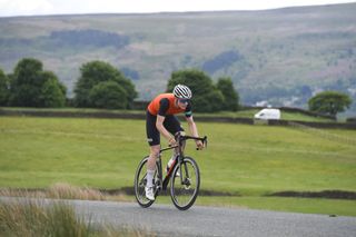 Image shows a rider cycling outdoors.