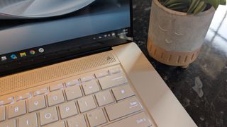The Zenbook S 16 photographed on a dark marble surface with potted plants in the background.