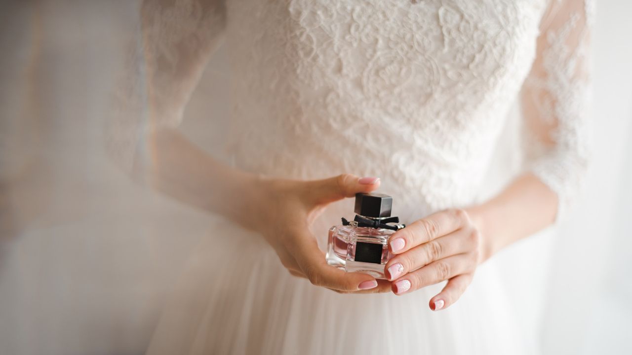 woman holding a bottle of fragrance on her wedding day