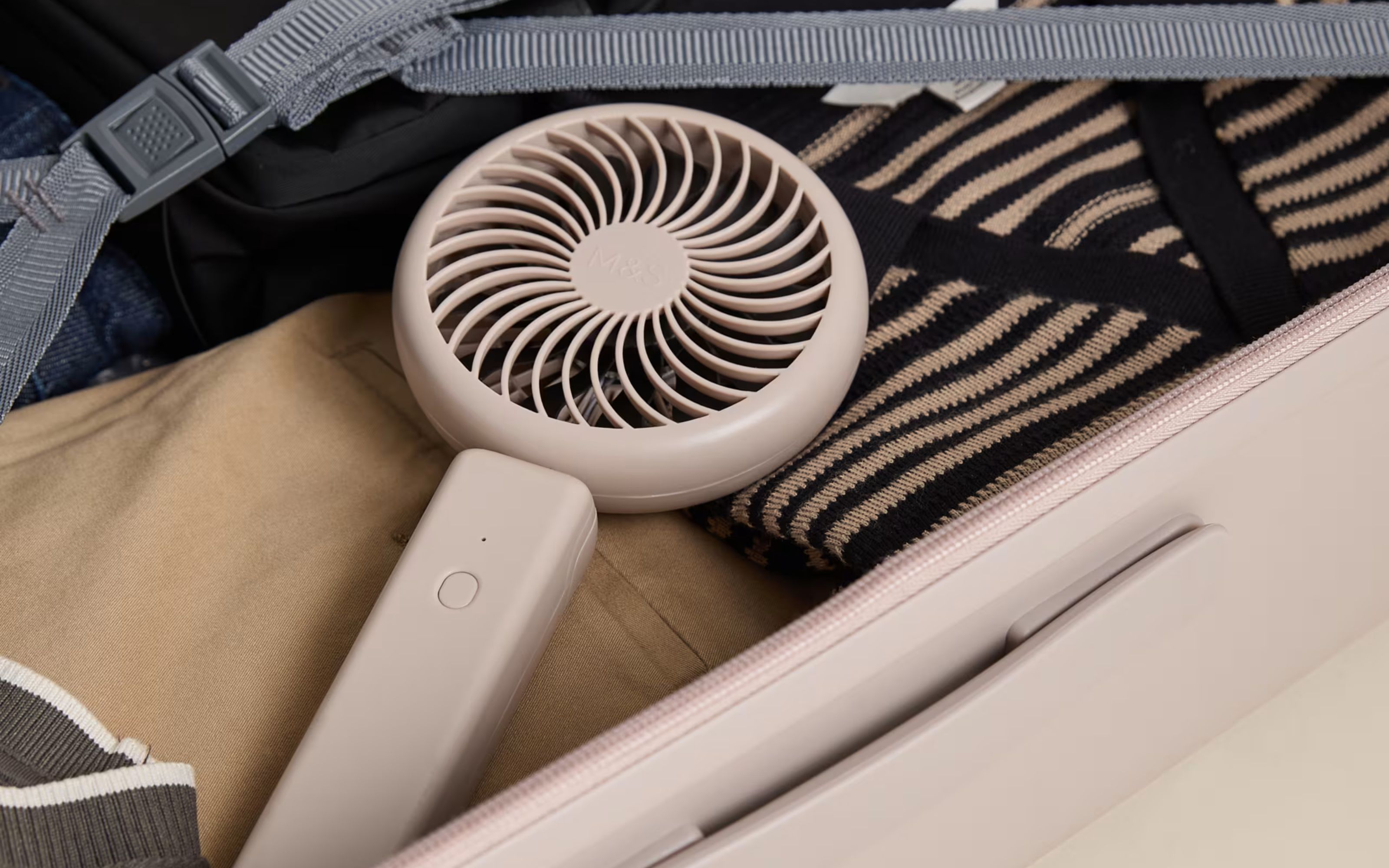 Portable fan in beige in suitcase around clothing