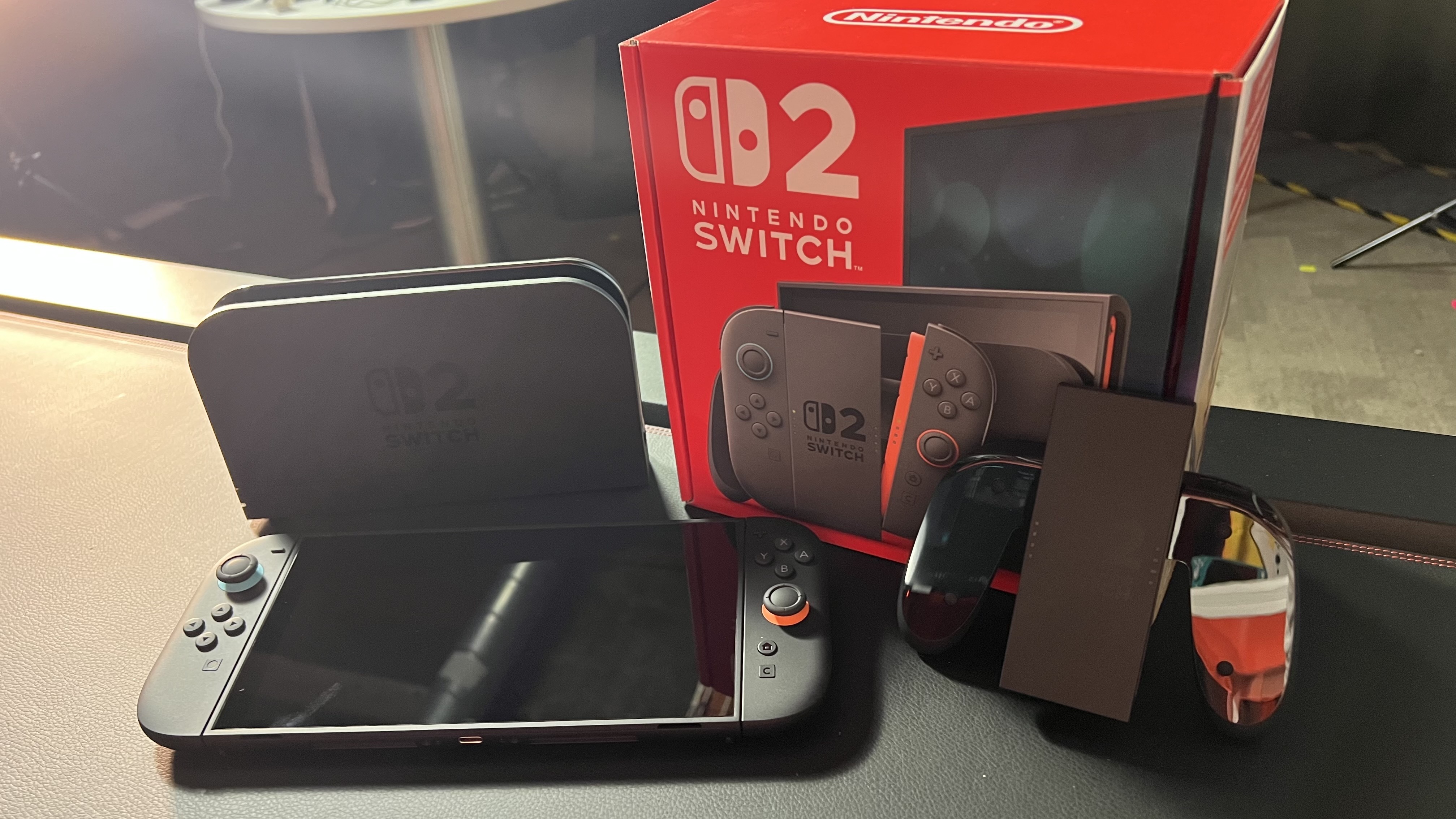 Nintendo Switch 2, Joy-Con attachment, dock, and box on a black desk