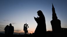 A woman walks past a cellphone tower in Moscow as the city grapples with internet blackouts. 