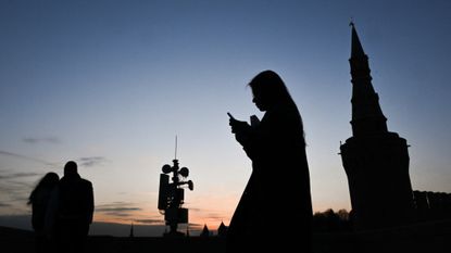 A woman walks past a cellphone tower in Moscow as the city grapples with internet blackouts. 