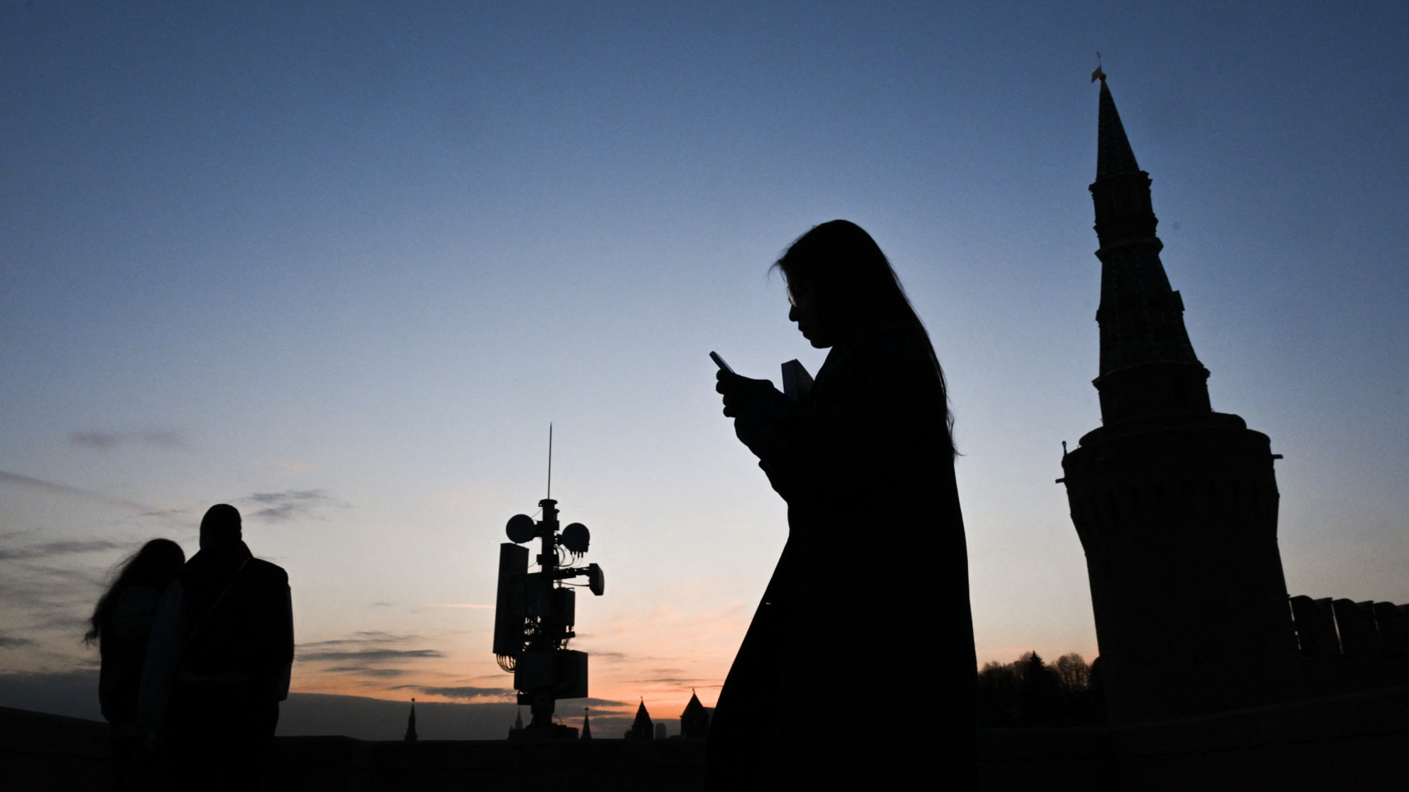 A woman walks past a cellphone tower in Moscow as the city grapples with internet blackouts. 